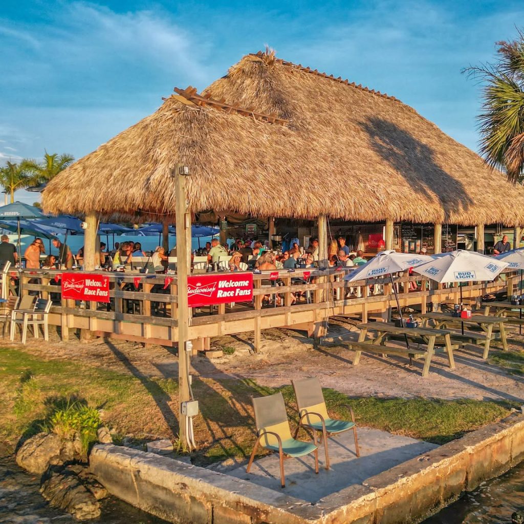 Evie’s at Spanish Point tiki bar with waterfront seating and umbrellas at golden hour.
