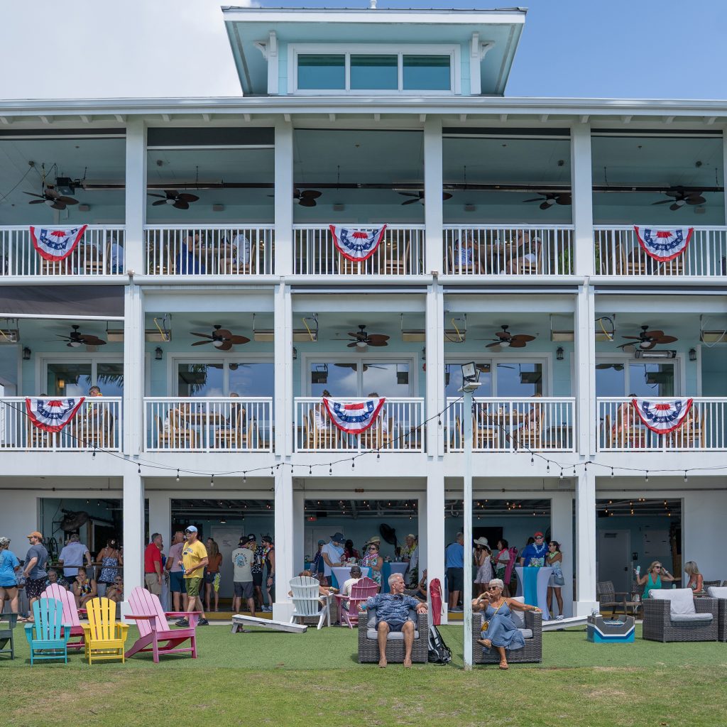 Exterior of The Point building with balconies, patriotic bunting, lawn seating, and guests outside.
